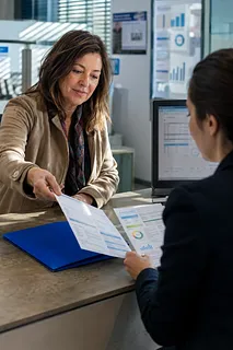 オフィスの窓口で担当者が申請書類を利用者に渡す様子